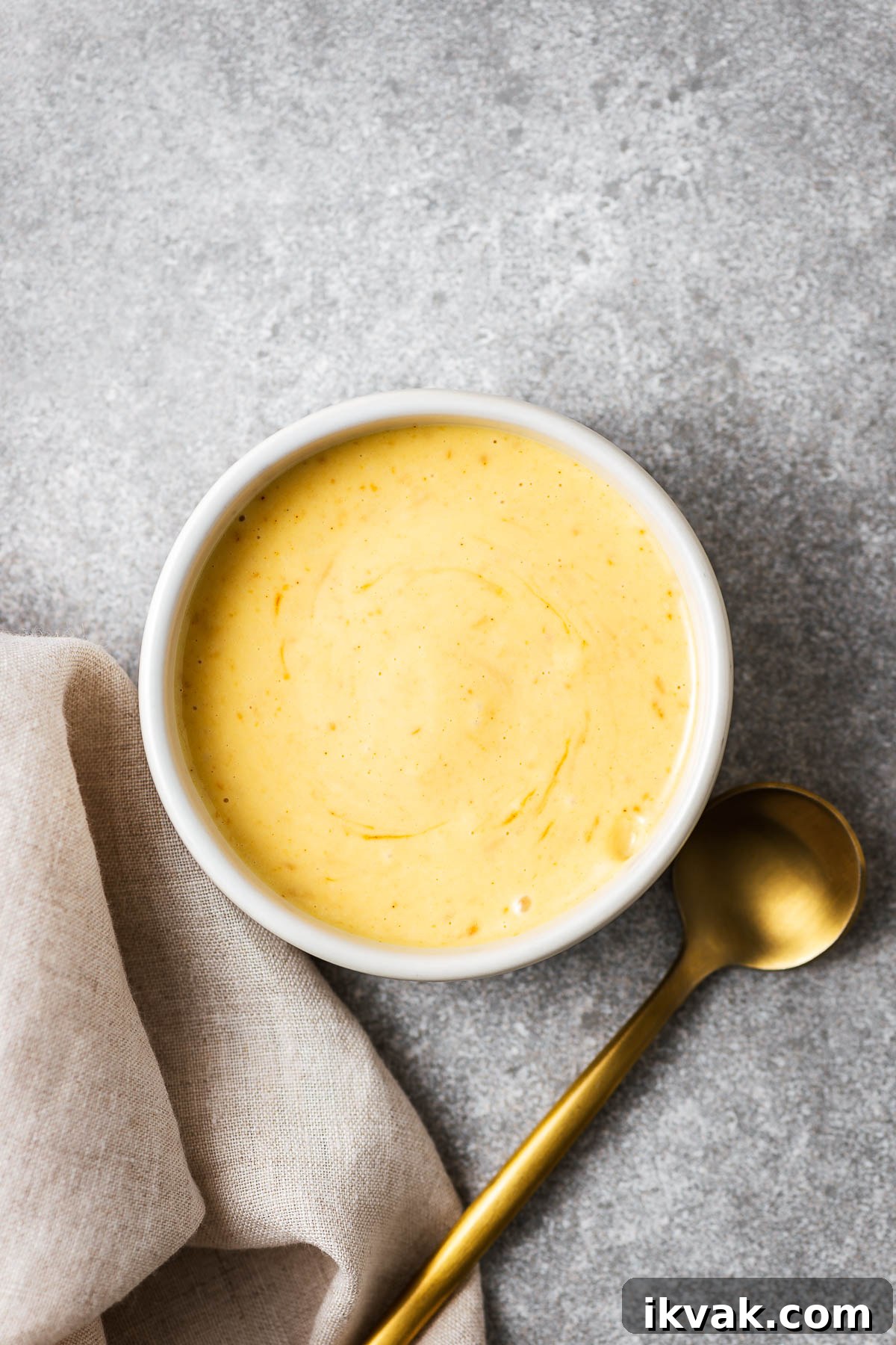 Golden miso mayo in a small ceramic bowl next to a serving spoon.