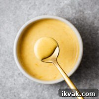 Golden miso mayo is scooped with a small teaspoon. The creamy mayonnaise coats the teaspoon.