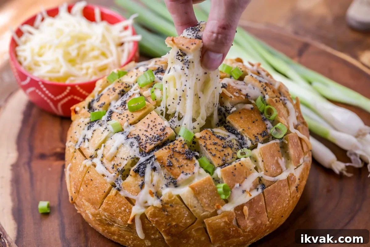 Pull Apart Bread is a favorite appetizer and perfect for sharing. There is cheesy, delicious goodness in every bite! Pulling a piece from the pull apart bread appetizer.