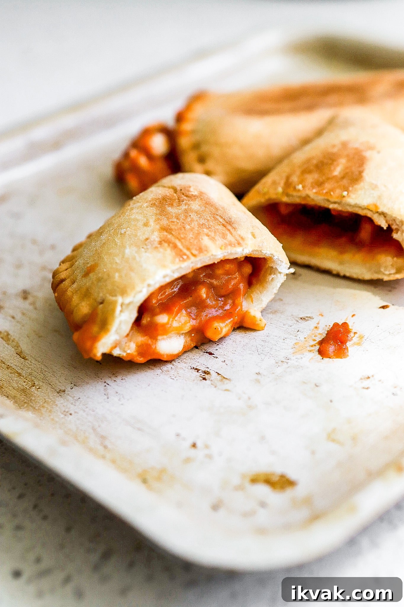 Crispy Air Fryer Frozen Pizza Pops Recipe 6 Side view of easy pepperoni pizza pockets cut in half on air fryer tray.