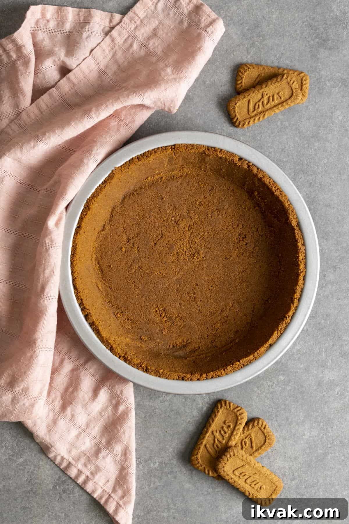 Biscoff pie crust on a gray table top with a pink tea towel.