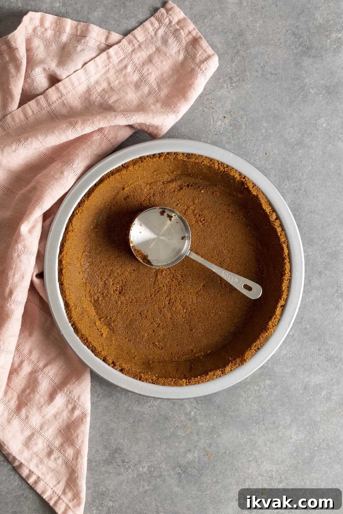 Biscoff cookie pie crust in a pie pan with a measuring cup inside.