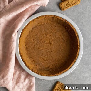 Biscoff pie crust on a gray table top with a pink tea towel.