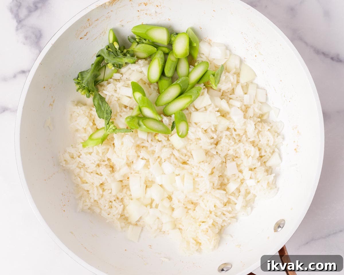 Adding the gai lan and diced yellow onions to the rice.