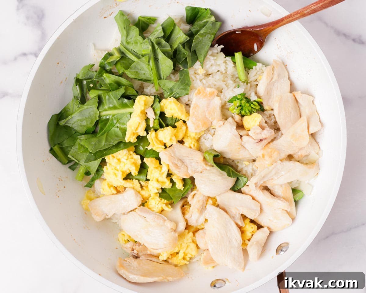 Adding the gai lan leaves, chicken, and eggs to the rice.