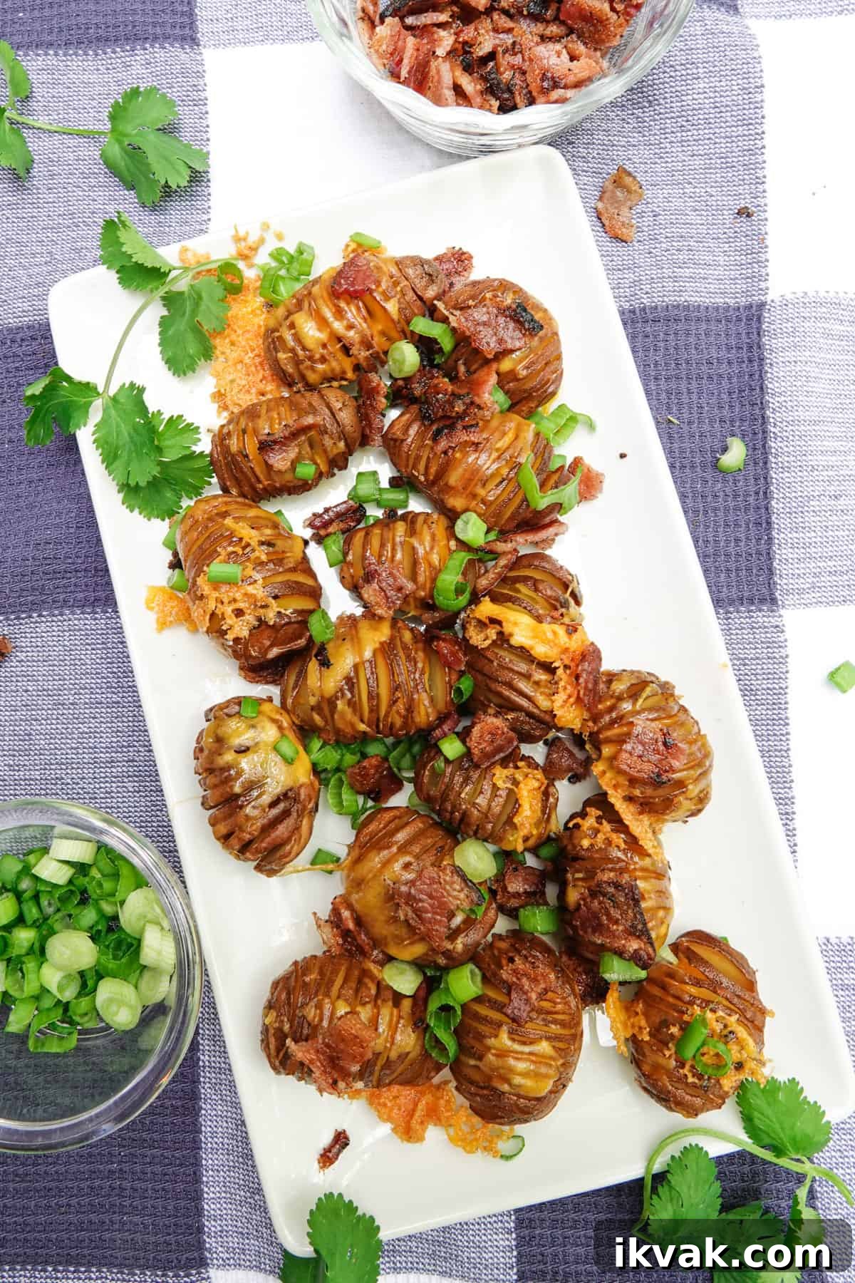 hasselback potatoes on white serving dish with green onions sprinkled on top