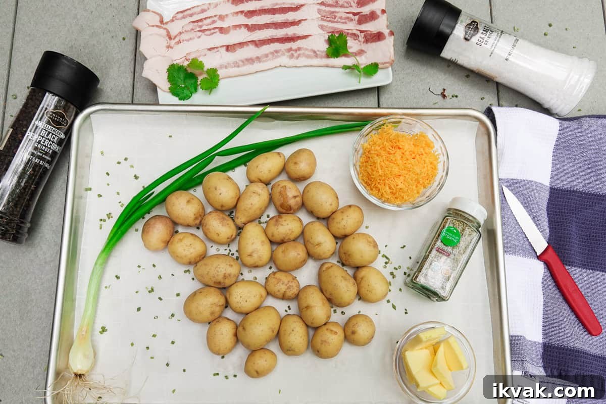 Petite gold potatoes on baking sheet with bacon, green onion, butter, and cheese surrounding the dish
