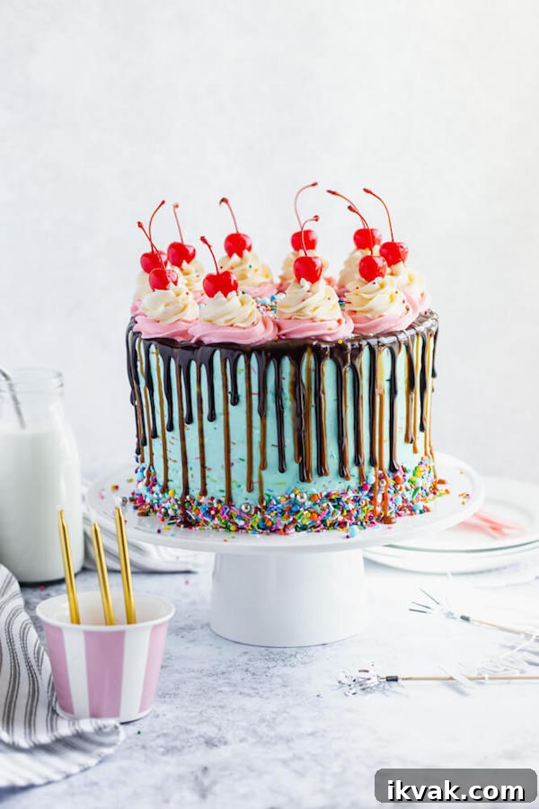 chocolate cake filled with vanilla sprinkle, caramel and chocolate buttercream and covered in a teal sprinkle frosting, topped with maraschino cherries and decorated with more sprinkles.
