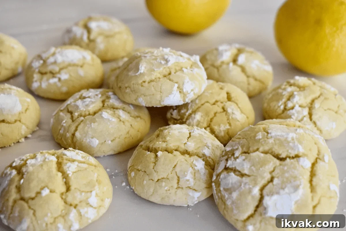 soft lemon cookies on a white countertop with lemons behind them. 