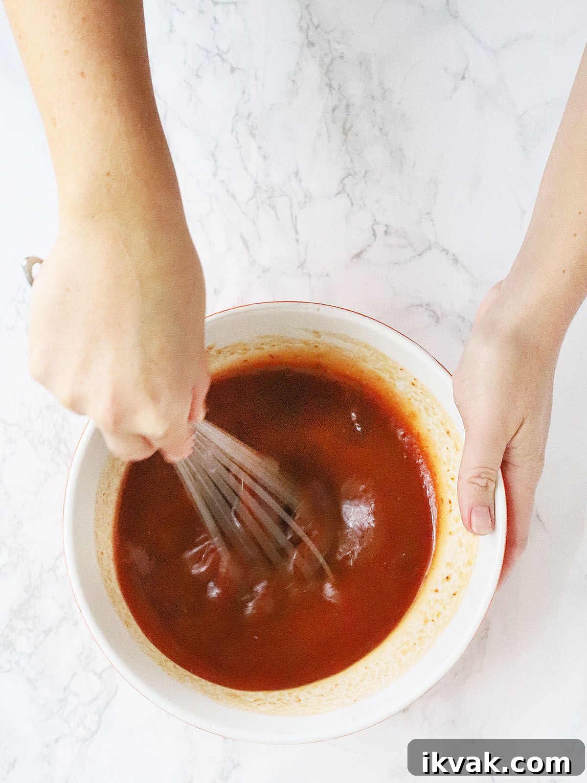 hands whisking together the bourbon apricot glaze ingredients