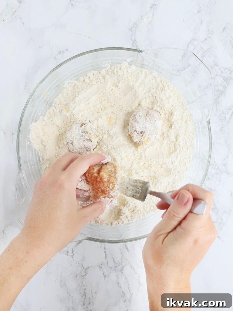 hands coating the chicken meatballs in flour