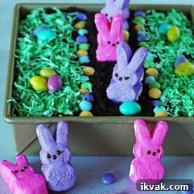 An Easter dirt cake for kids with coconut grass, m and ms, and peeps.