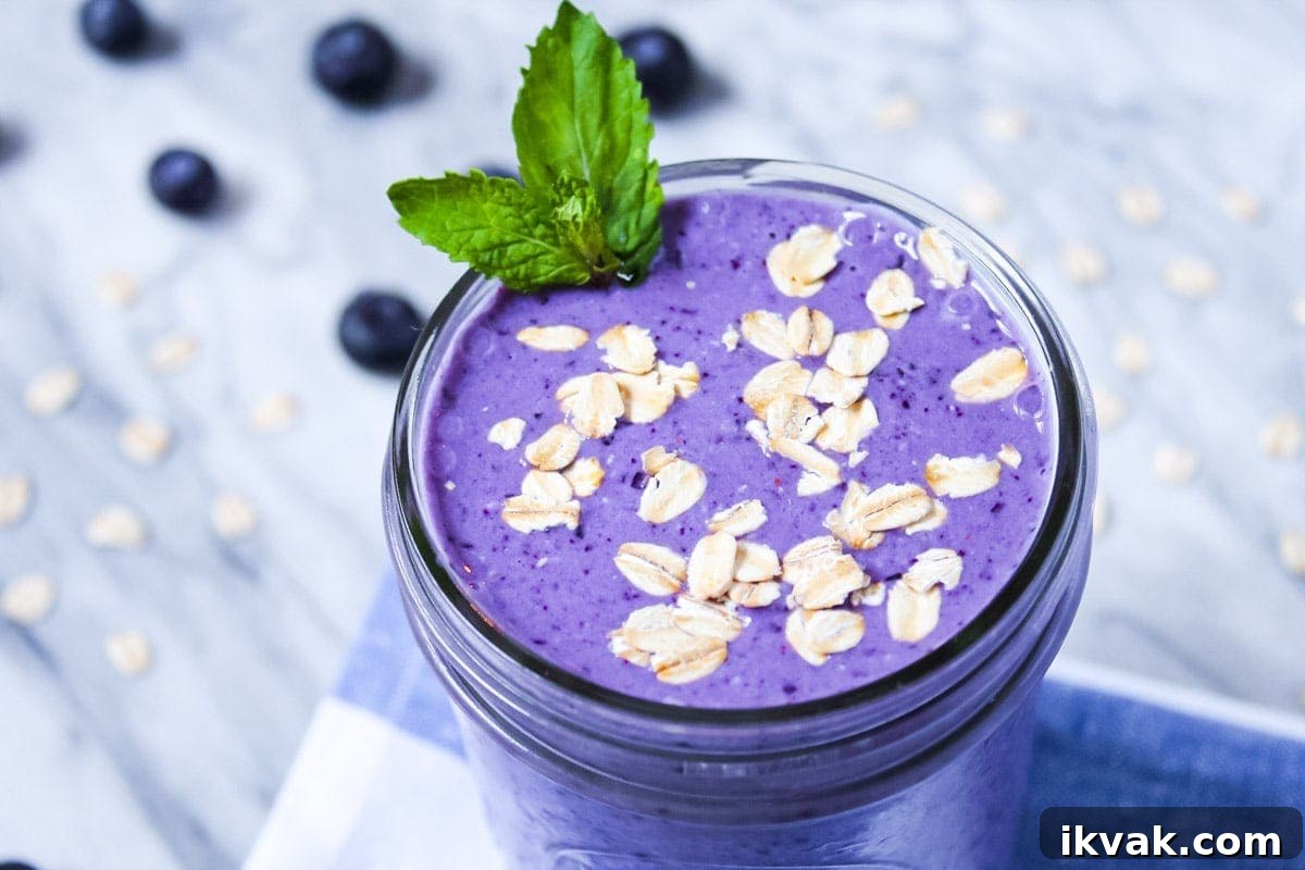 Blueberry Muffin Smoothie Recipe: Creamy Breakfast Shake 4 Picture of a purple blueberry smoothie garnished with mint and oats.