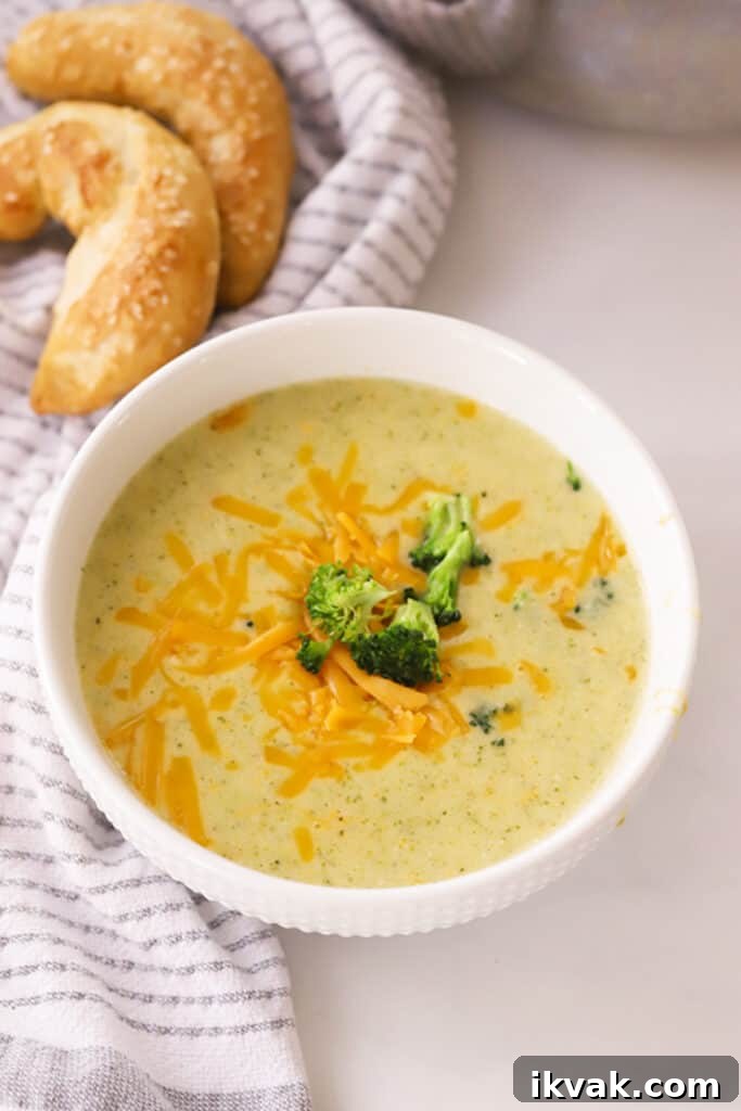 Creamy Broccoli Potato Cheese Soup Recipe for Comforting Meals 2 Cheesy broccoli potato soup in a white bowl with broccoli on top.