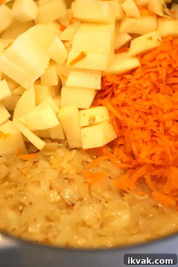 Creamy Broccoli Potato Cheese Soup Recipe for Comforting Meals 3 Potatoes, caramelized onions, and shredded carrots in a pot ready to make potato broccoli cheese soup.