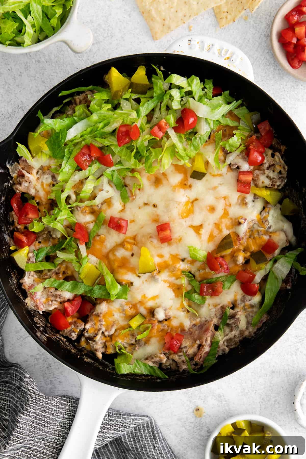 Loaded Cheeseburger Dip Recipe: Crowd-Pleasing Party Appetizer 6 Cheeseburger dip topped with lettuce, tomatoes, and pickles.