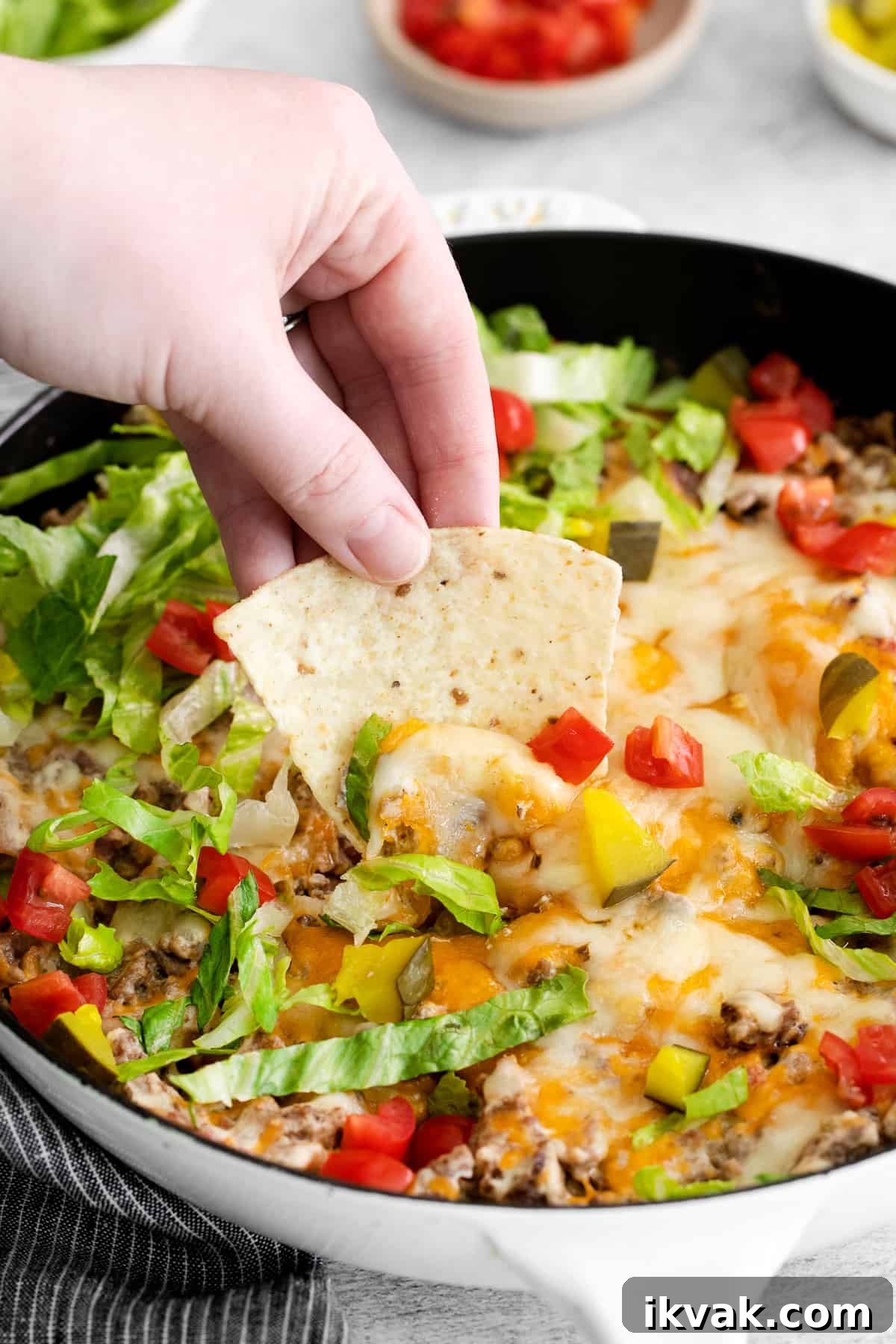 Loaded Cheeseburger Dip Recipe: Crowd-Pleasing Party Appetizer 7 A chip taking a scoop of cheeseburger dip.