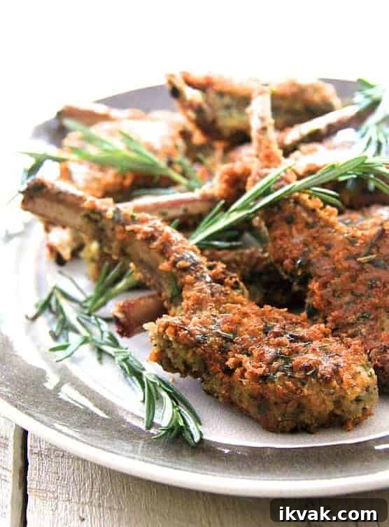 Close-up photo of Parmesan and Herb-Crusted Lamb Chops on gray-rimmed platter garnished with rosemary.