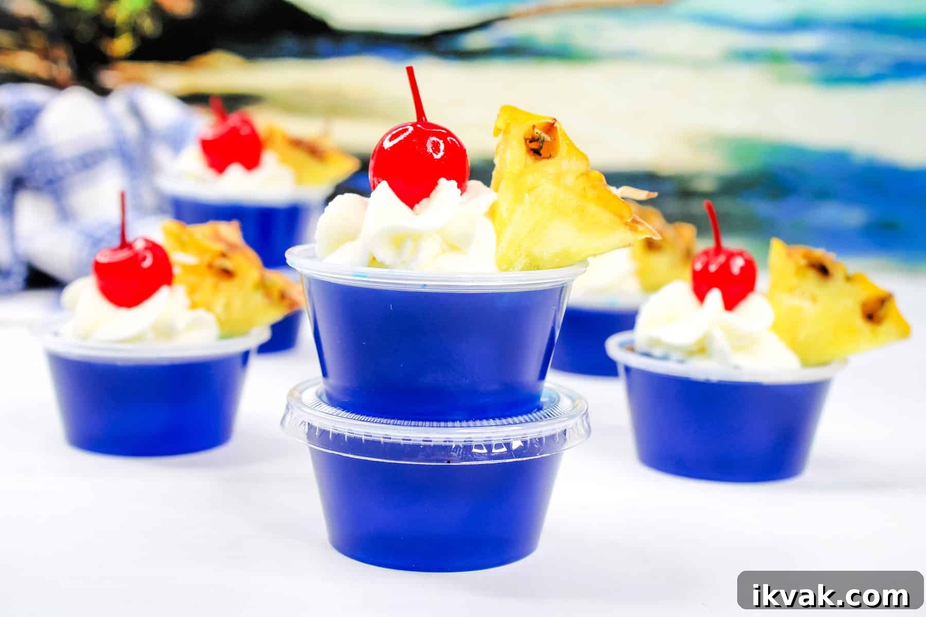 Malibu Coconut Rum Jello Shots Recipe for Summer Parties 4 blue malibu rum jello shots topped with whipped cream, pineapple, and a cherry