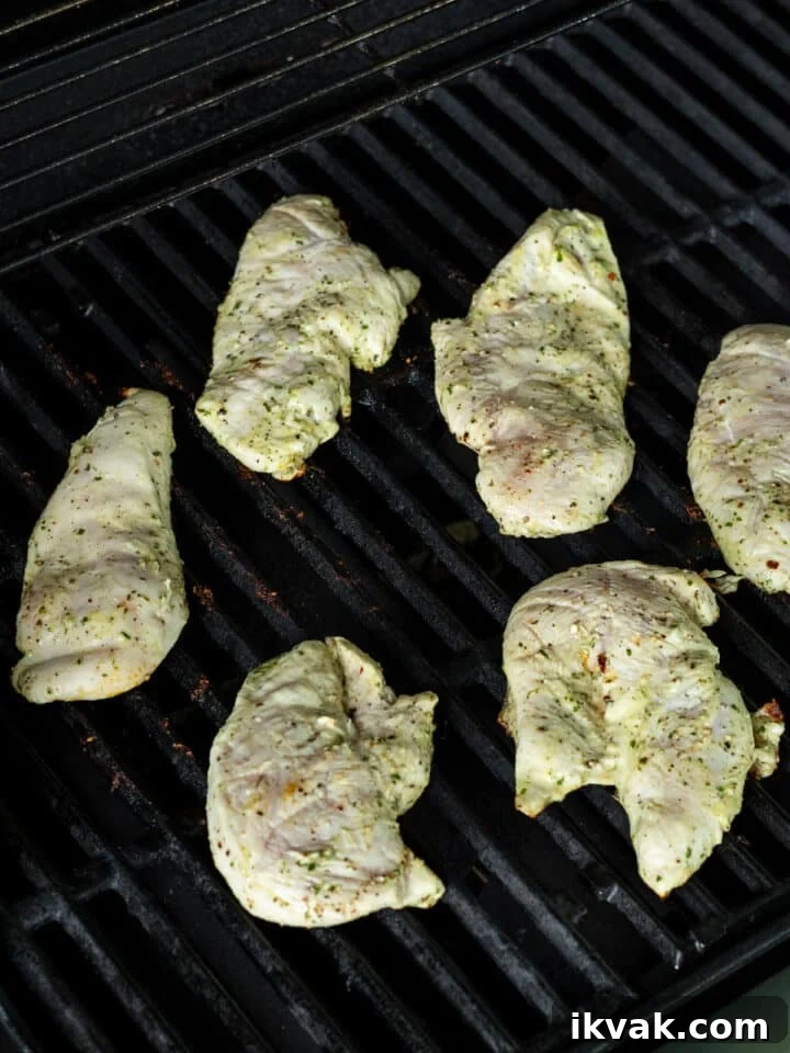Thin-sliced chicken breast cooking on grill grates 