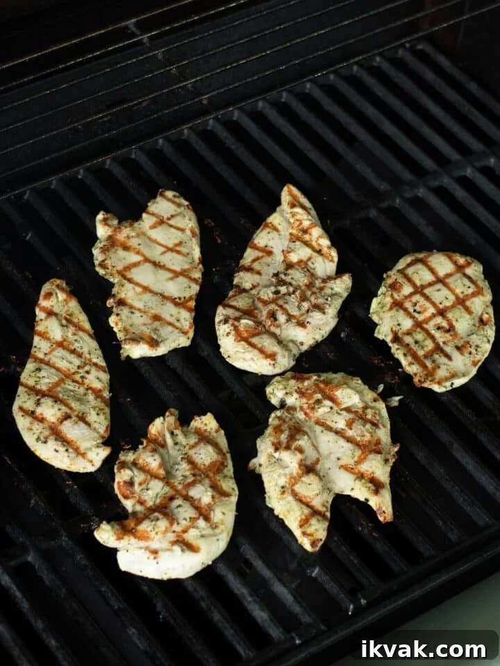 Chicken cutlets with golden brown grill marks cooking on a grill
