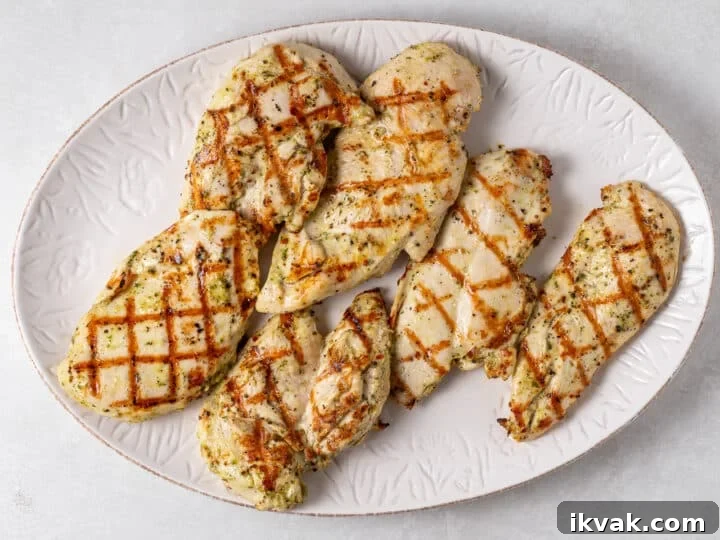 Grilled chicken breast with golden hatch marks resting on a white platter