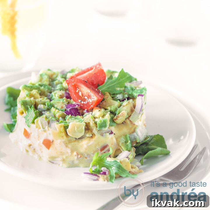 A square photo of a salad of smoked chicken and avocado on a white plate, topped with quartred cherry tomatoes on a white background