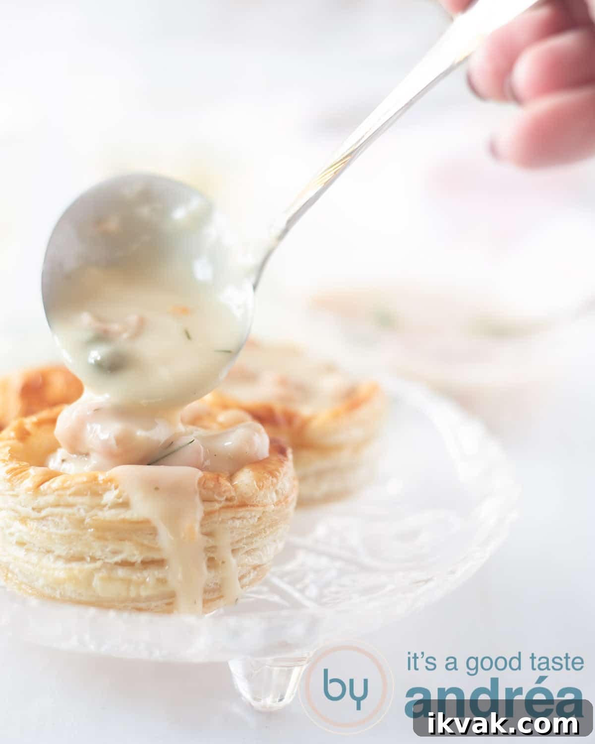 A pastry case on a glass plate. A sauce spoon scoops a little shrimp ragout into the tray