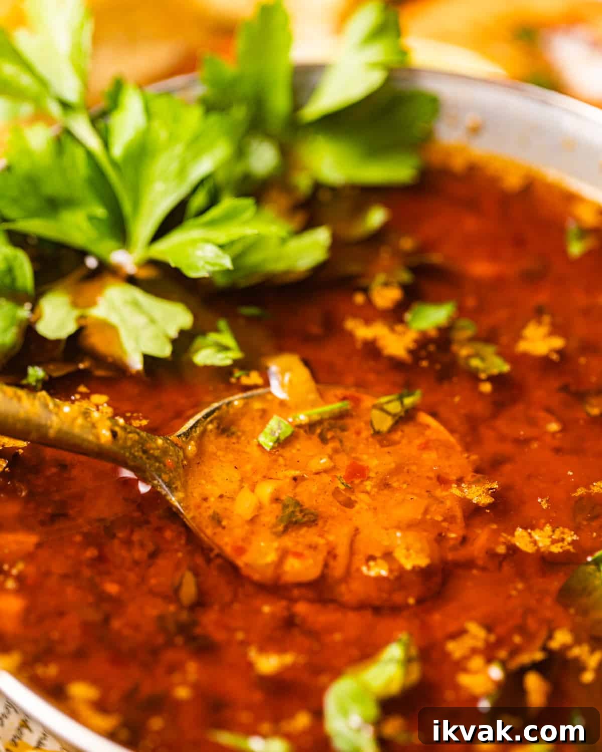 an up close photo of seafood boil sauce in a bowl garnished with parsley.