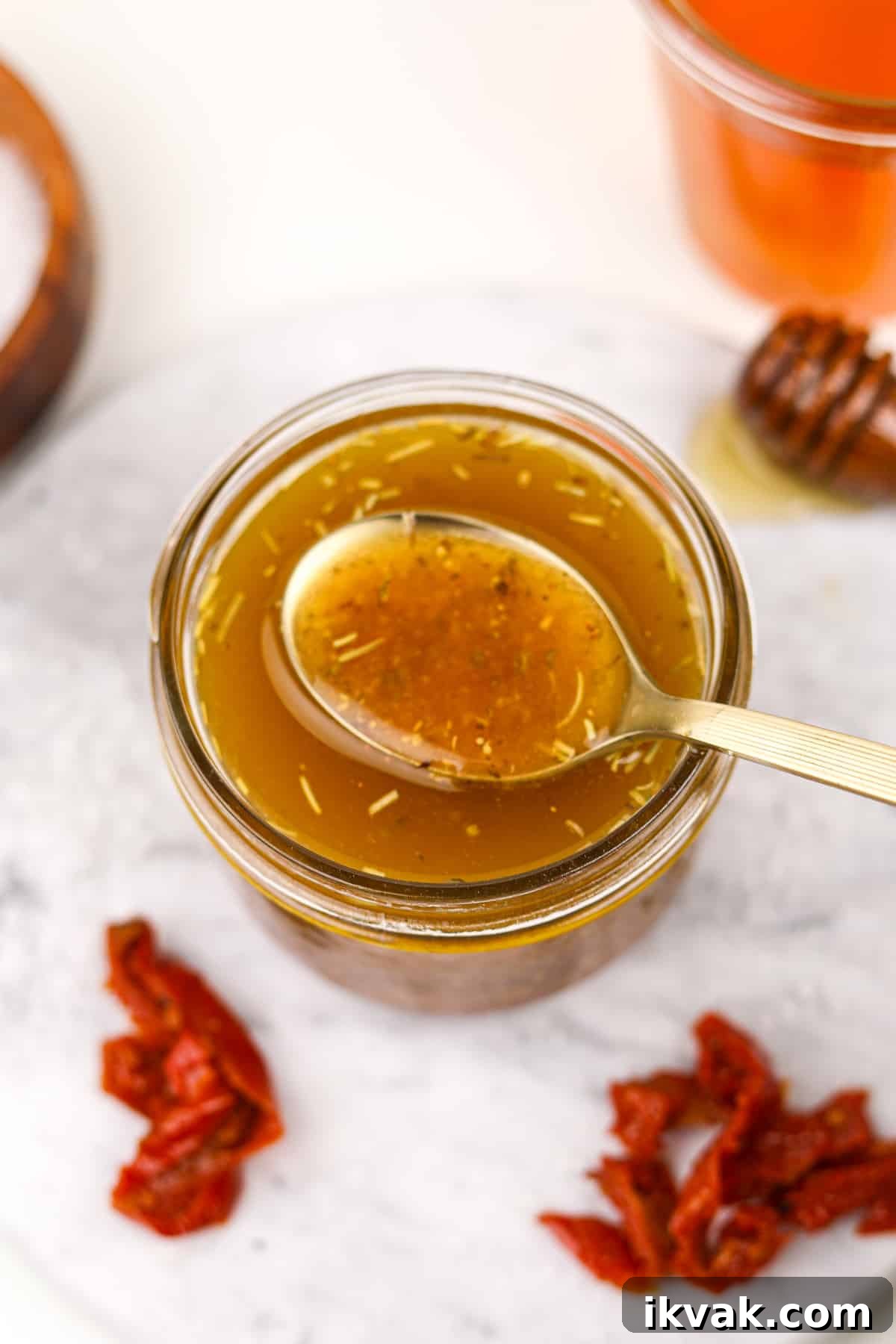 A gold spoon taking a small amount of homemade dressing from a jar.