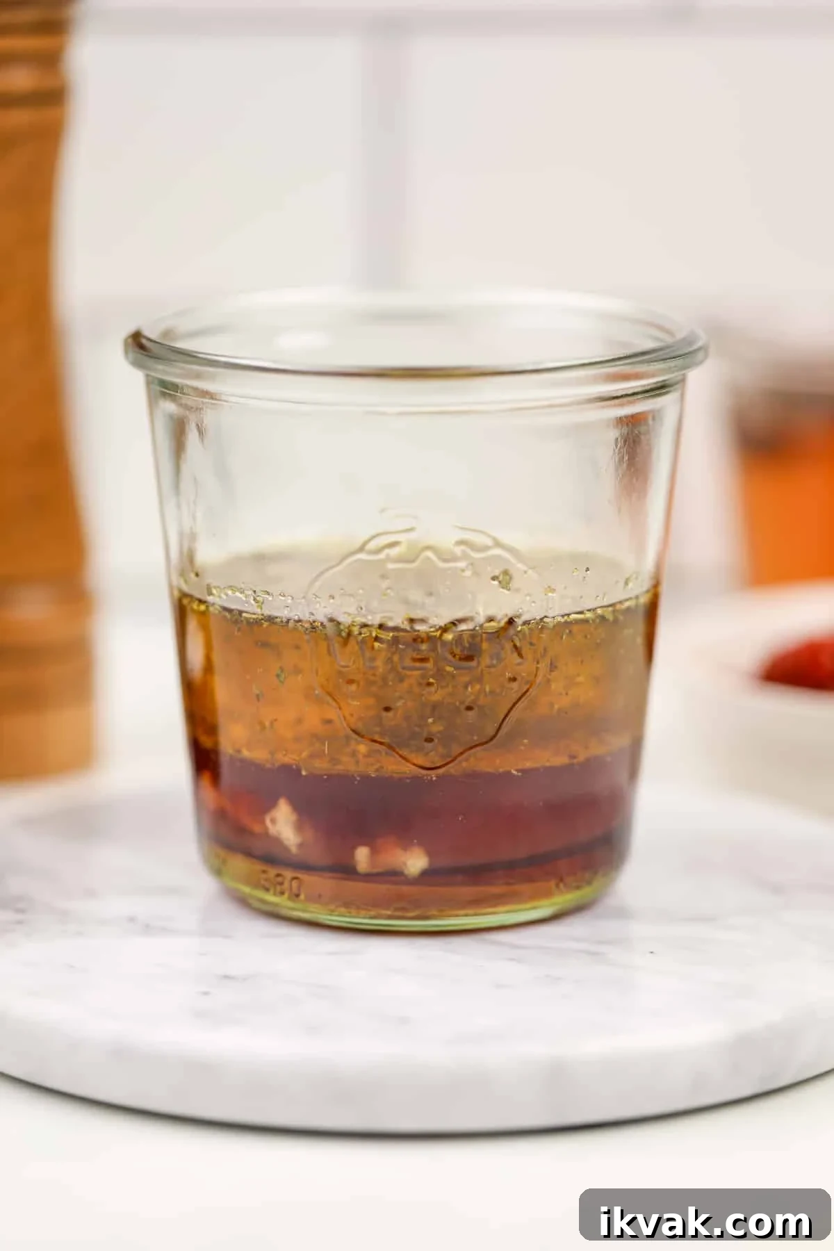 A glass jar featuring layers of oil and vinegar.
