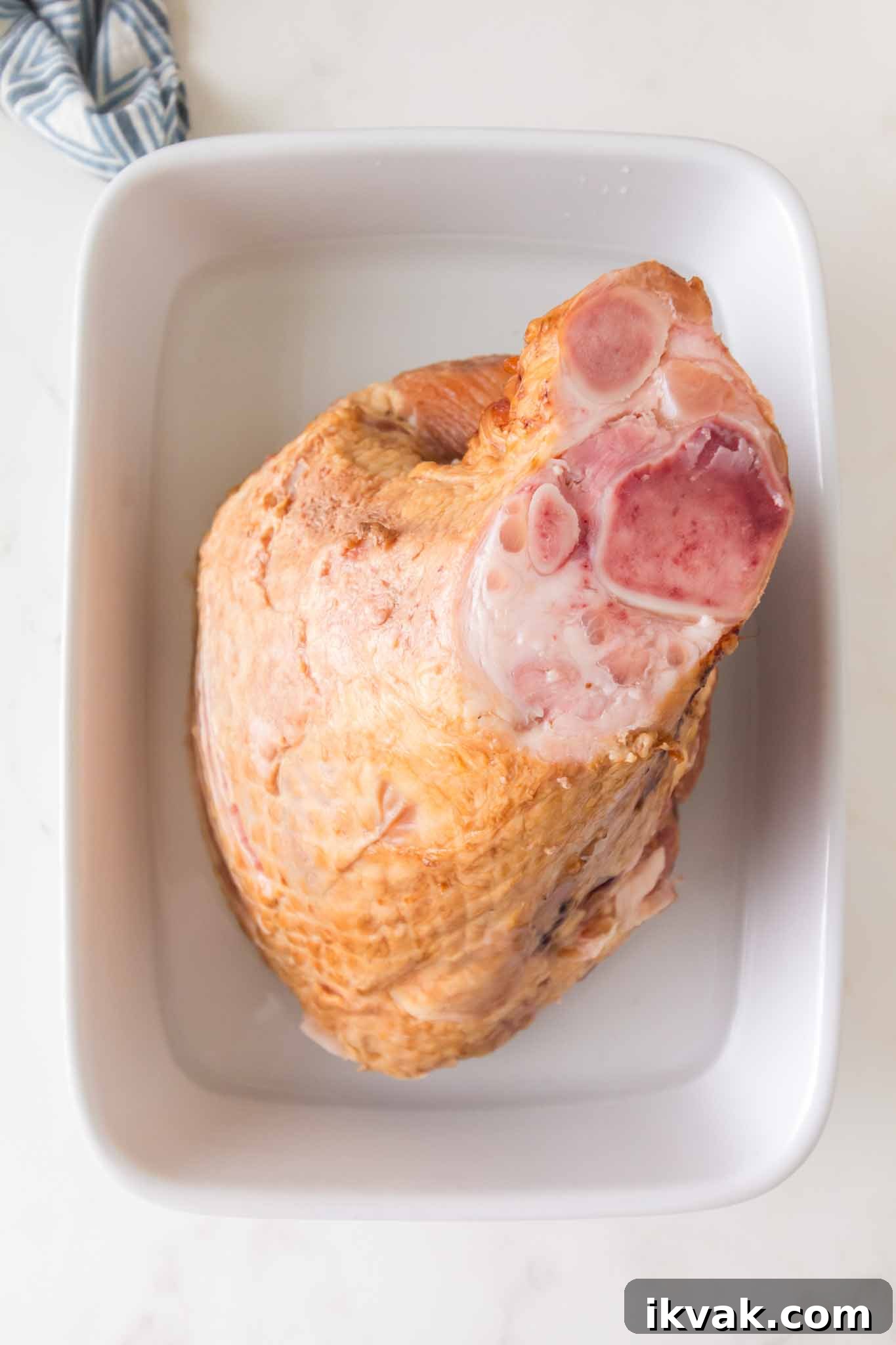 Honey-Baked Ham with Brown Sugar Glaze Recipe 4 Spiral cut ham placed in baking dish with water before cooking for honey baked ham recipe - Hostess At Heart