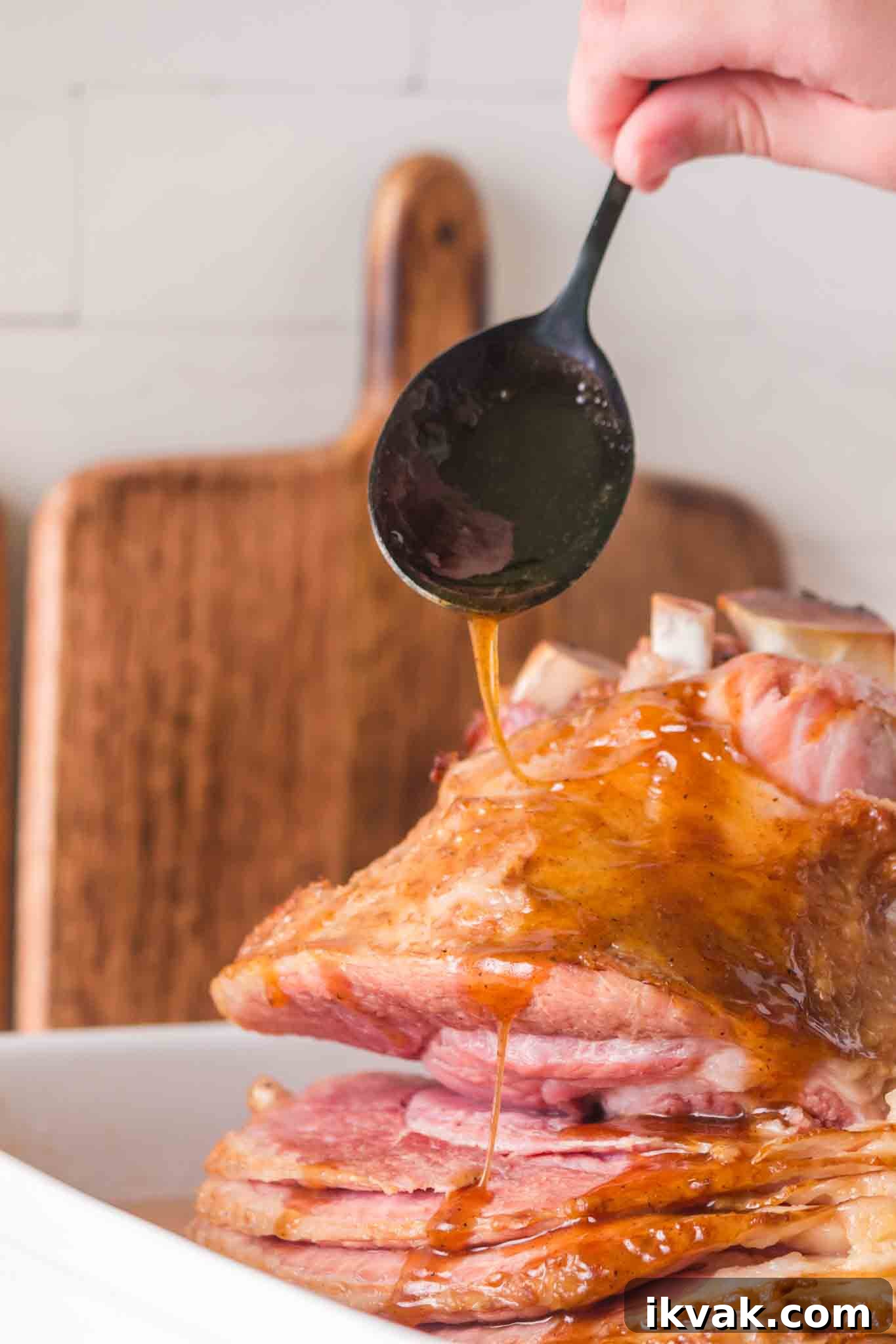 Honey-Baked Ham with Brown Sugar Glaze Recipe 6 Spooning brown sugar glaze onto spiral ham with for caramelizing - Hostess At Heart
