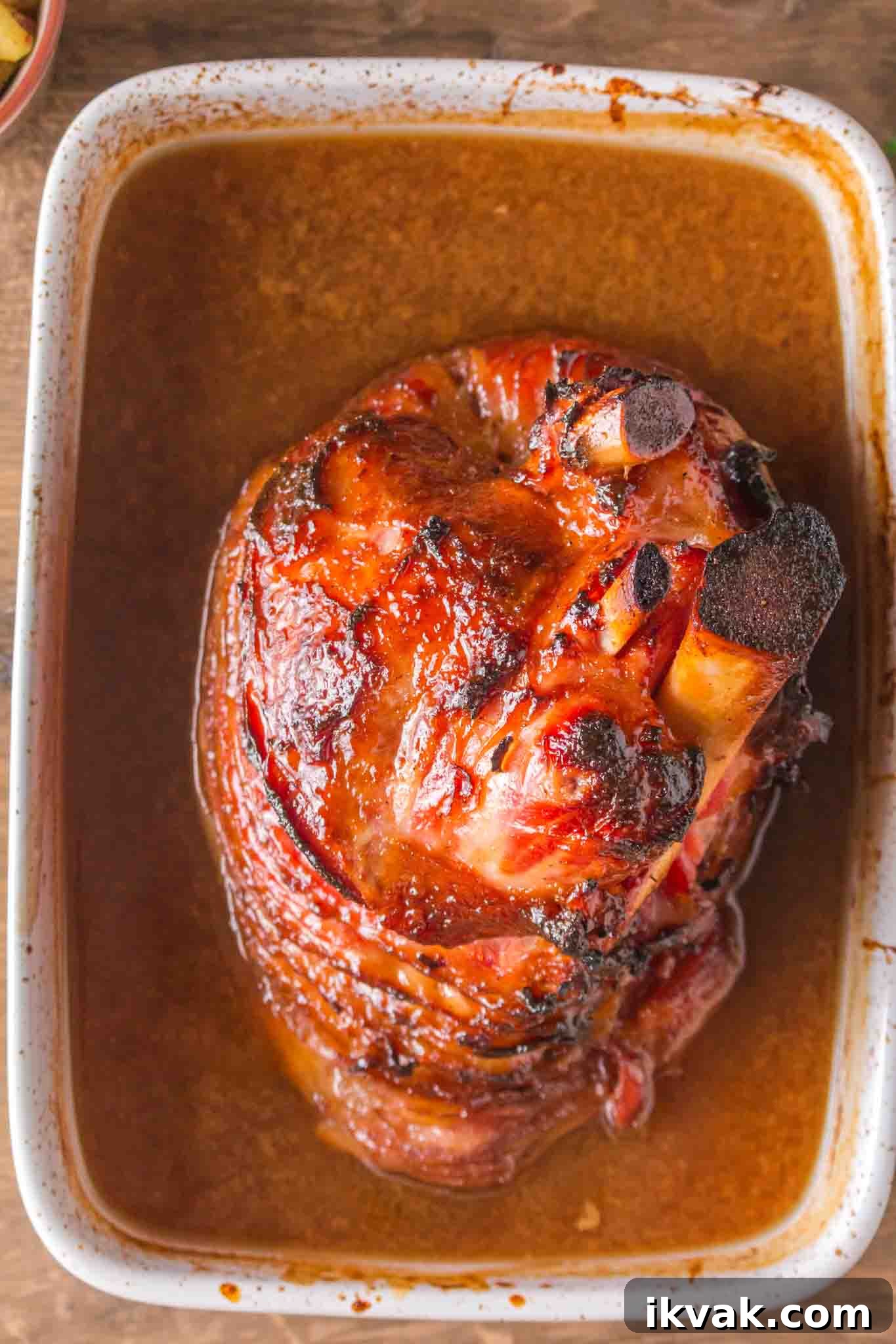 Honey-Baked Ham with Brown Sugar Glaze Recipe 7 Overhead view of glazed spiral ham in baking dish with golden caramelized coating - Hostess At Heart