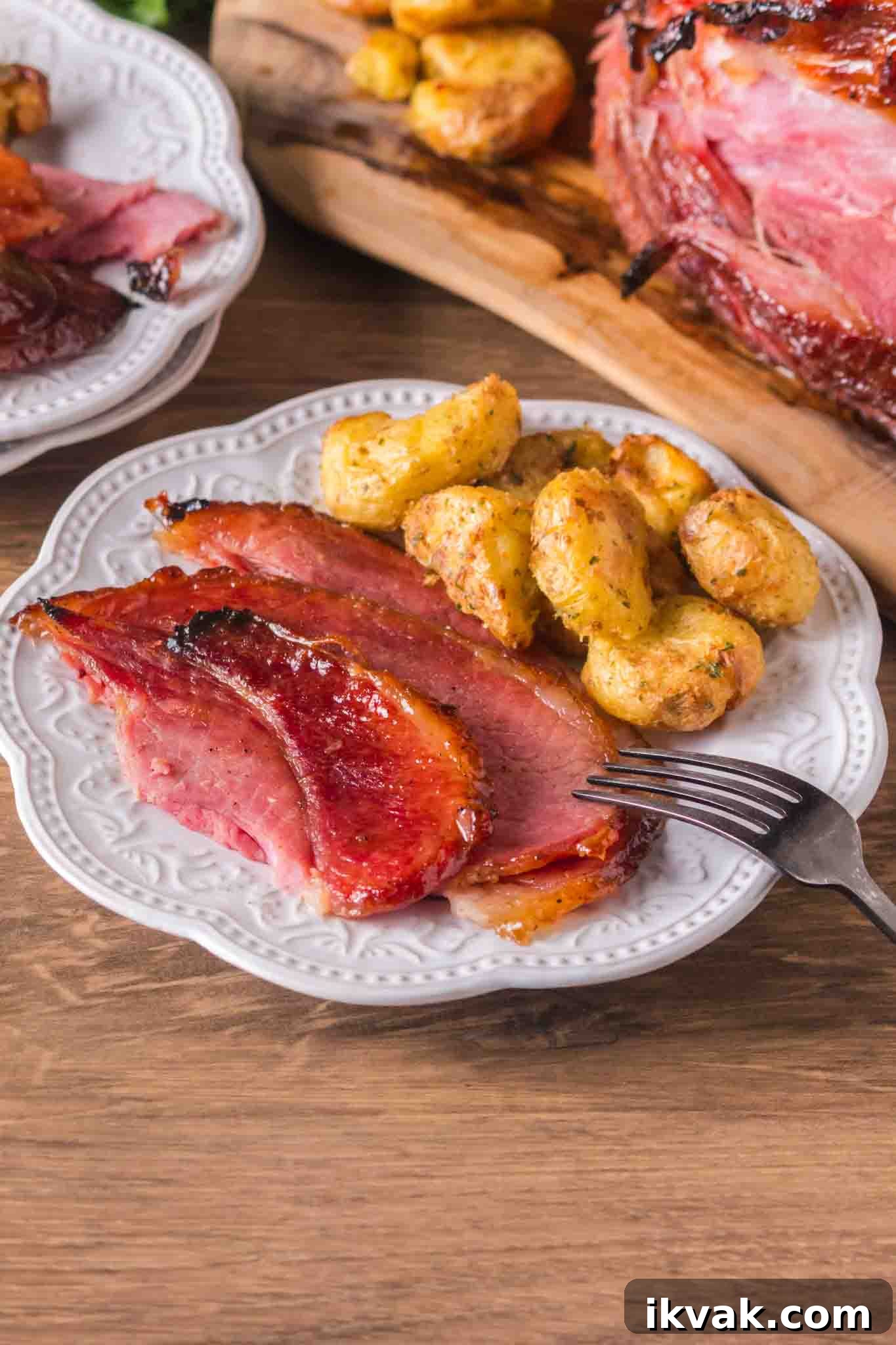Honey-Baked Ham with Brown Sugar Glaze Recipe 9 Glazed ham slices served on white plate with creamy smashed potatoes - Hostess At Heart
