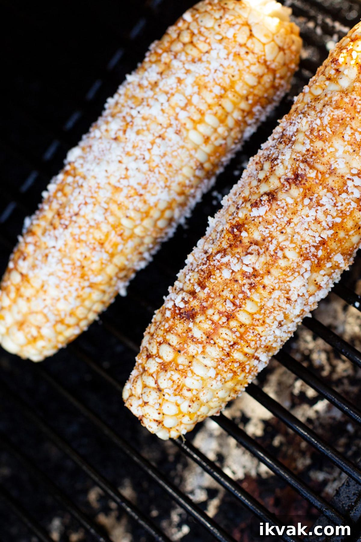 Two pieces of mexican corn on the cob on the grill.