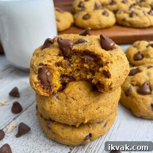 The best soft and chewy pumpkin chocolate chip cookies stacked on top of each other served with a glass of milk