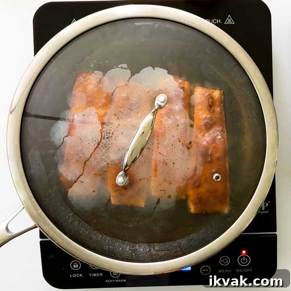 Honey Garlic Pan-Seared Salmon in a HexClad Skillet 11 Salmon cooking in a frying pan with a lid.