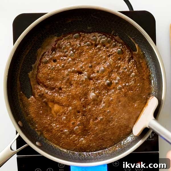 Honey Garlic Pan-Seared Salmon in a HexClad Skillet 9 Thickening the honey garlic butter sauce in a frying pan.