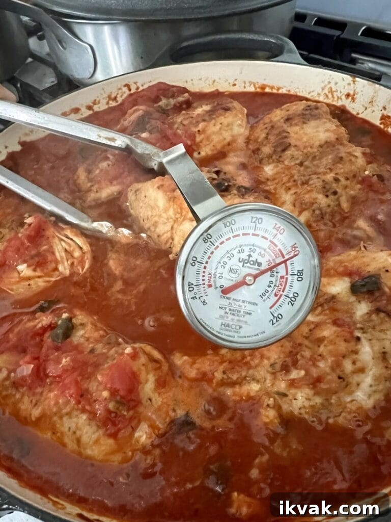 Checking the internal temperature of the chicken with a stem thermometer.