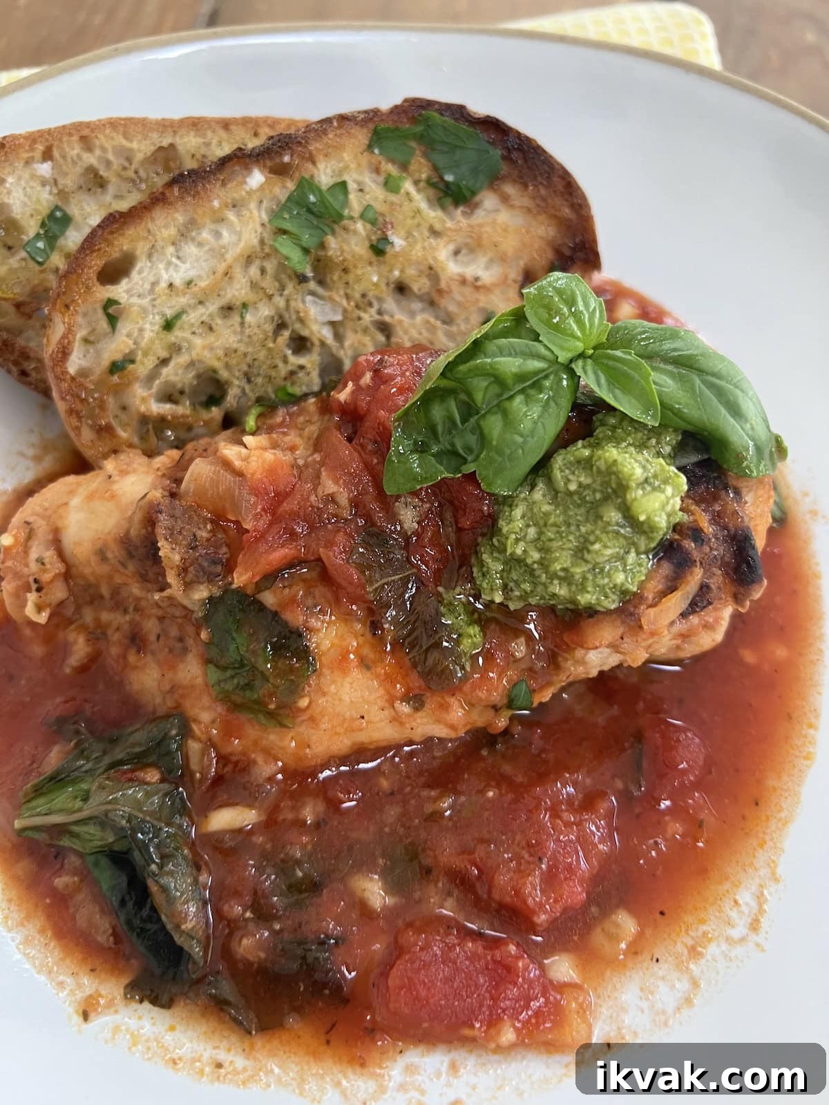 Easy Pomodoro Chicken on a white dinner plate with toasted bread and basil garnish.