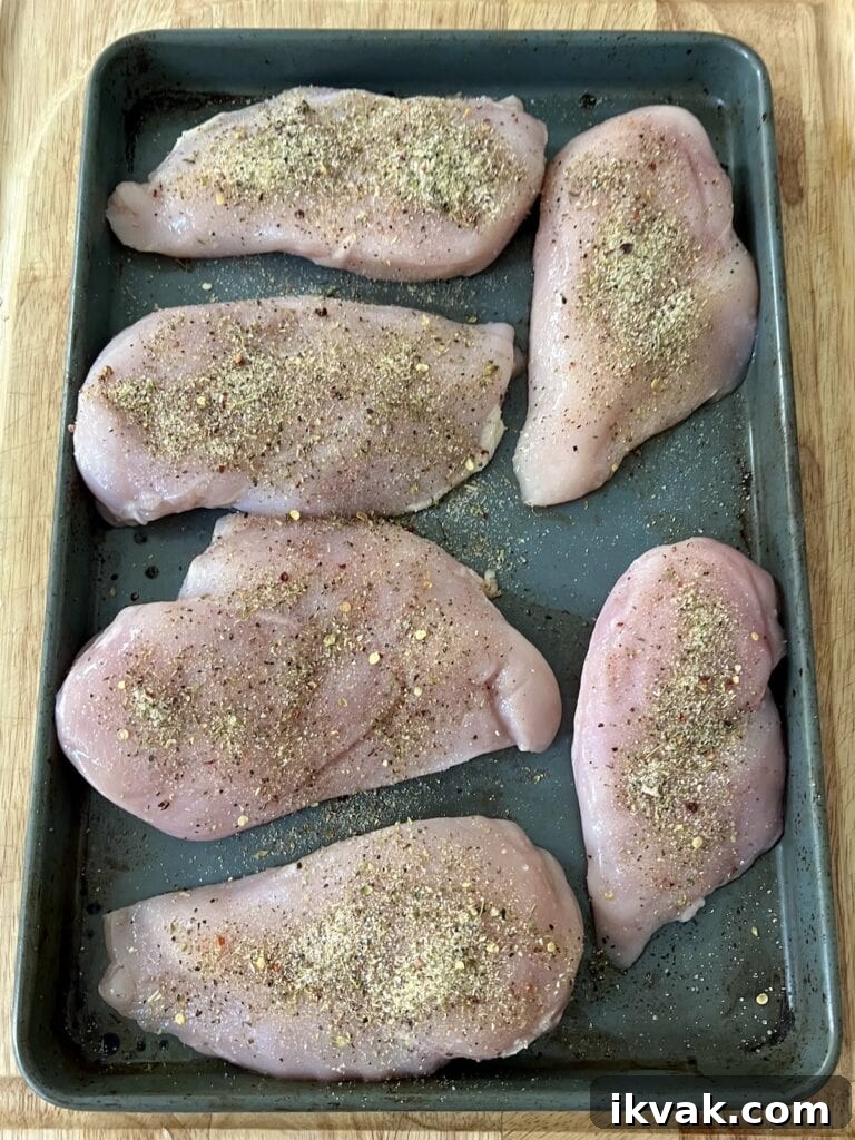 Chicken breasts sprinkled with salt and pepper on baking sheet.