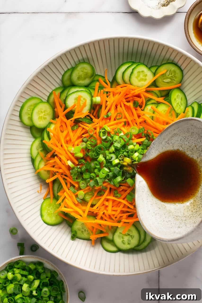 Crisp Cucumber and Carrot Salad with Tangy Dressing 5 pouring dressing on top of a cucumber carrot salad