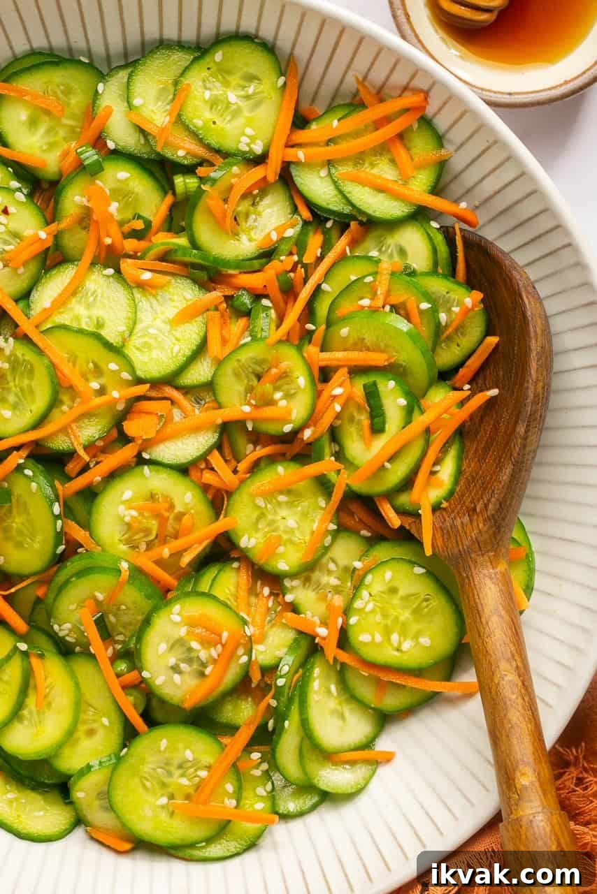 Crisp Cucumber and Carrot Salad with Tangy Dressing 7 a close up view of a cucumber salad in a large bowl with a wooden spoon