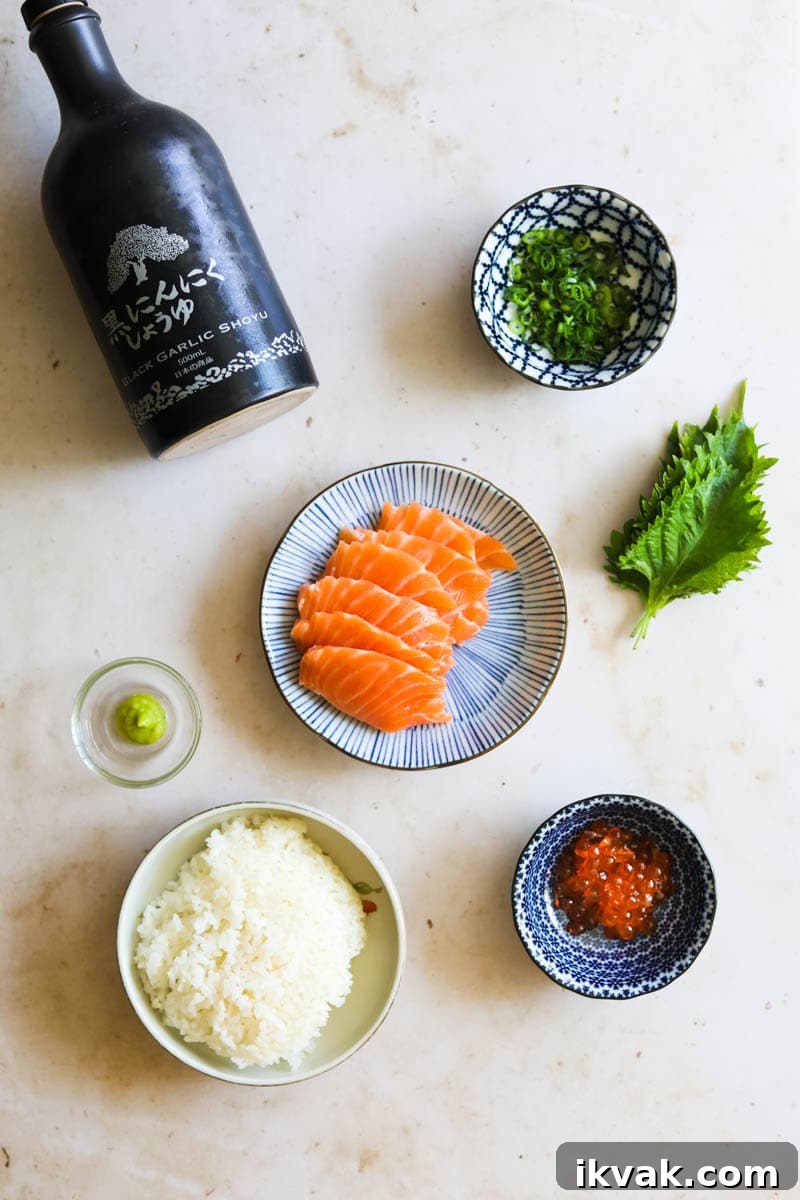 Ingredients to make salmon sashimi donburi with shiso, rice, Ikura, scallions, wasabi, and soy sauce.