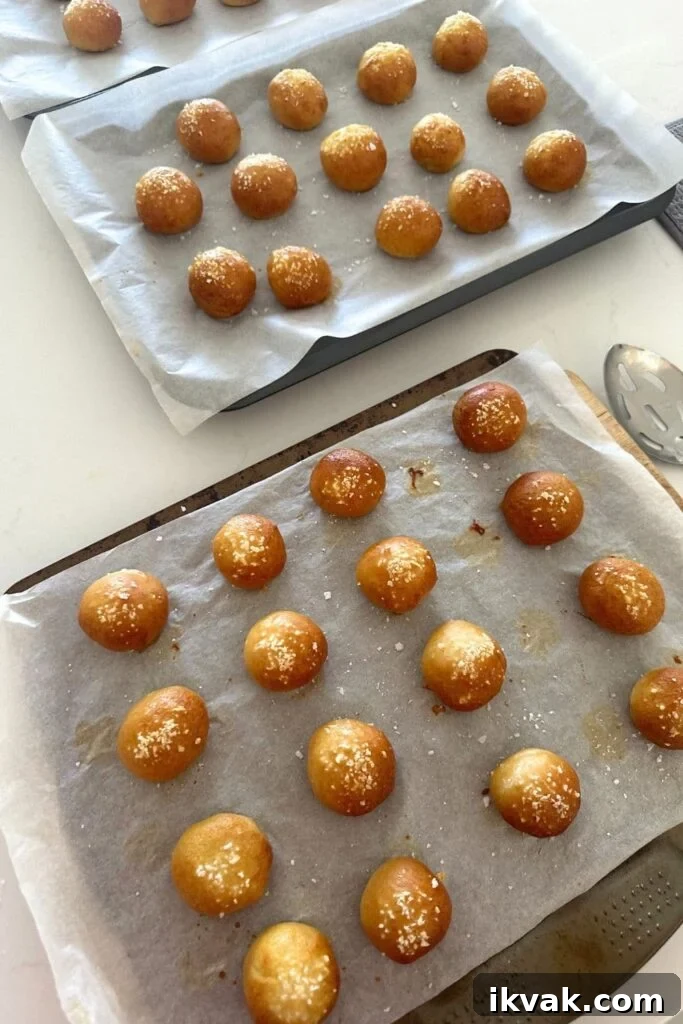 Freshly baked sourdough discard pretzel bites cooling on baking trays.