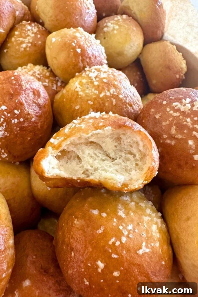 Close up photo of a sourdough discard pretzel bite. Someone has taken a bit and you can see the soft, chewy crumb of the interior. The other sourdough pretzel bites have been sprinkled in salt.