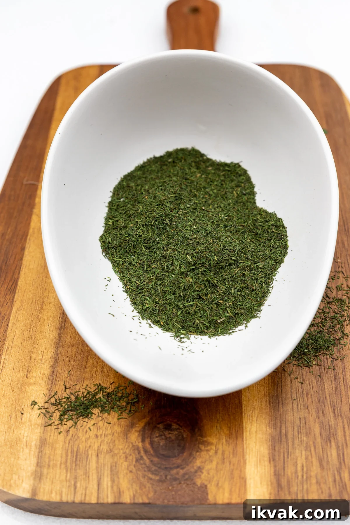 20 Flavorful Dill Substitutes for Cooking and Garnish 3 Dried dill in a small white bowl on a wooden chopping board.