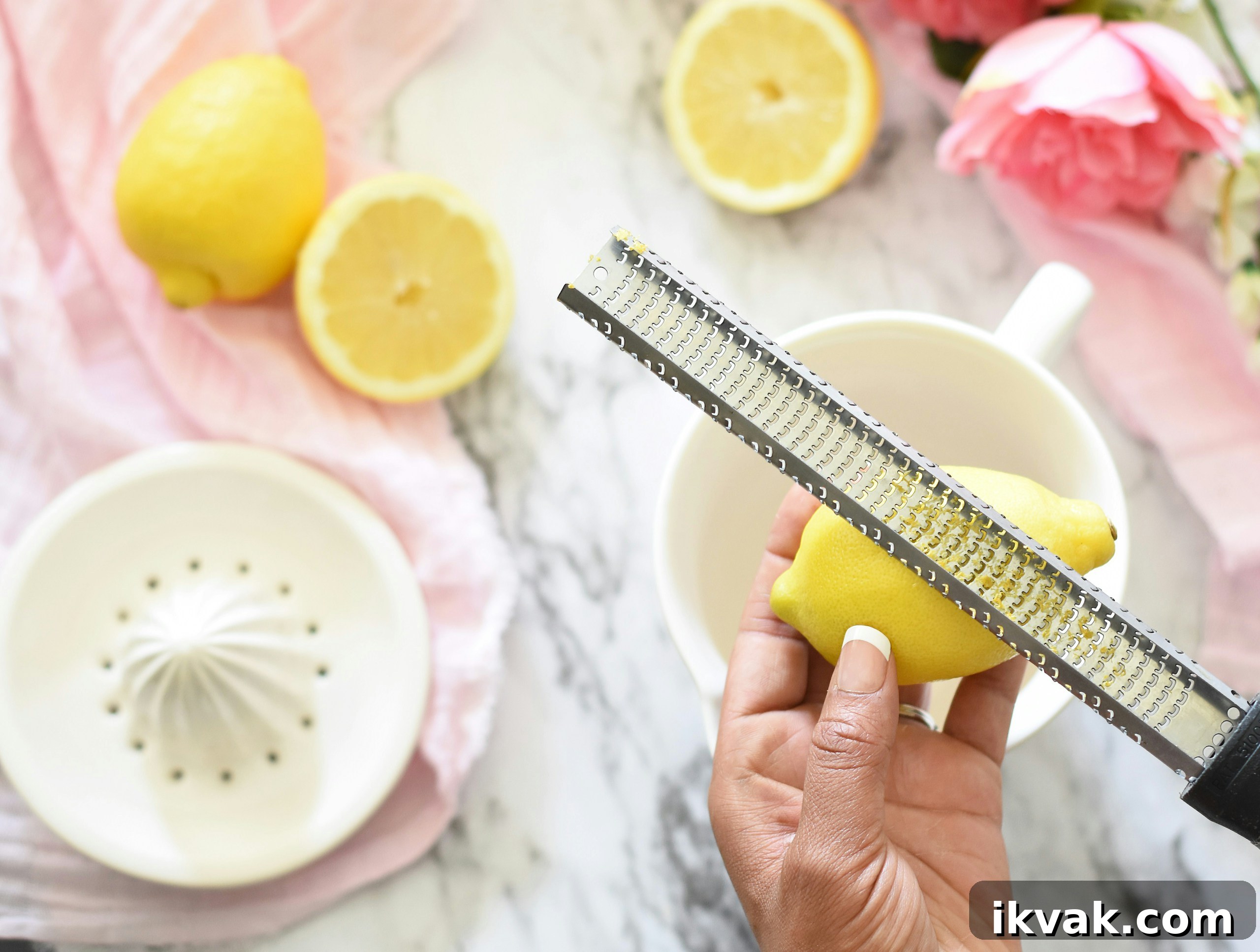 Person zesting a lemon with a grater.