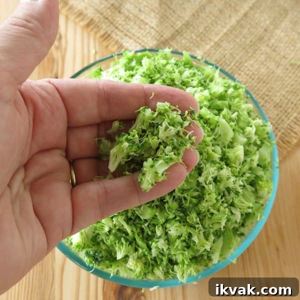 Bowl or riced broccoli with hand holding some of it